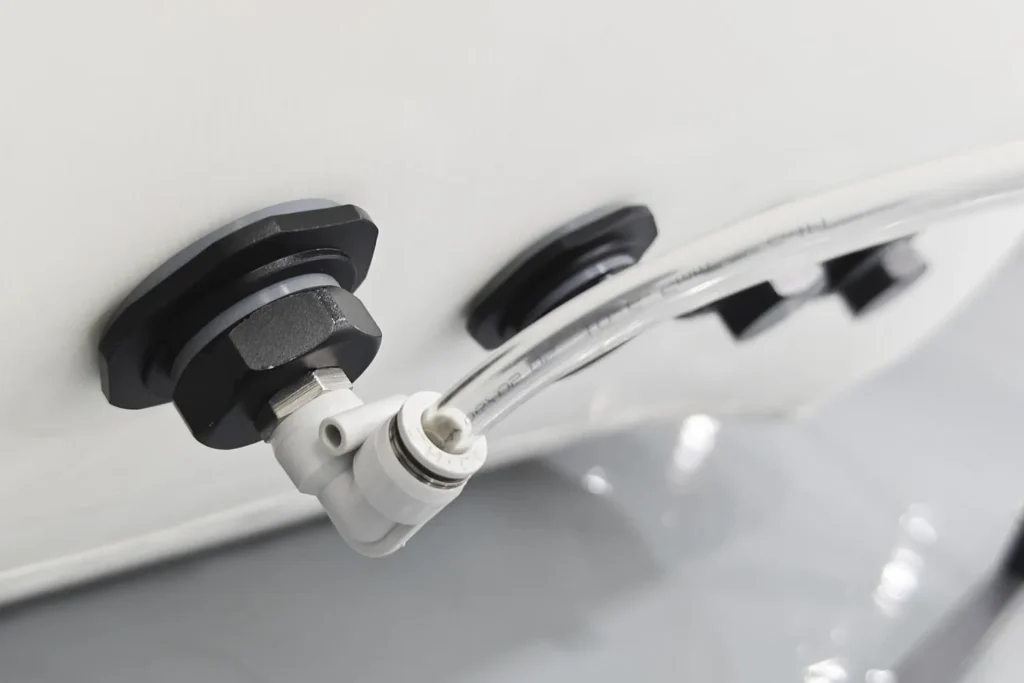 Detaljan prikaz bele naduvavajuće hiperbarične komore Dominium Wellness, model DW140MH, sa dva crna heksagonalna priključka. Providno crevo povezano je na jedan priključak i zakrivljeno ka kameri.