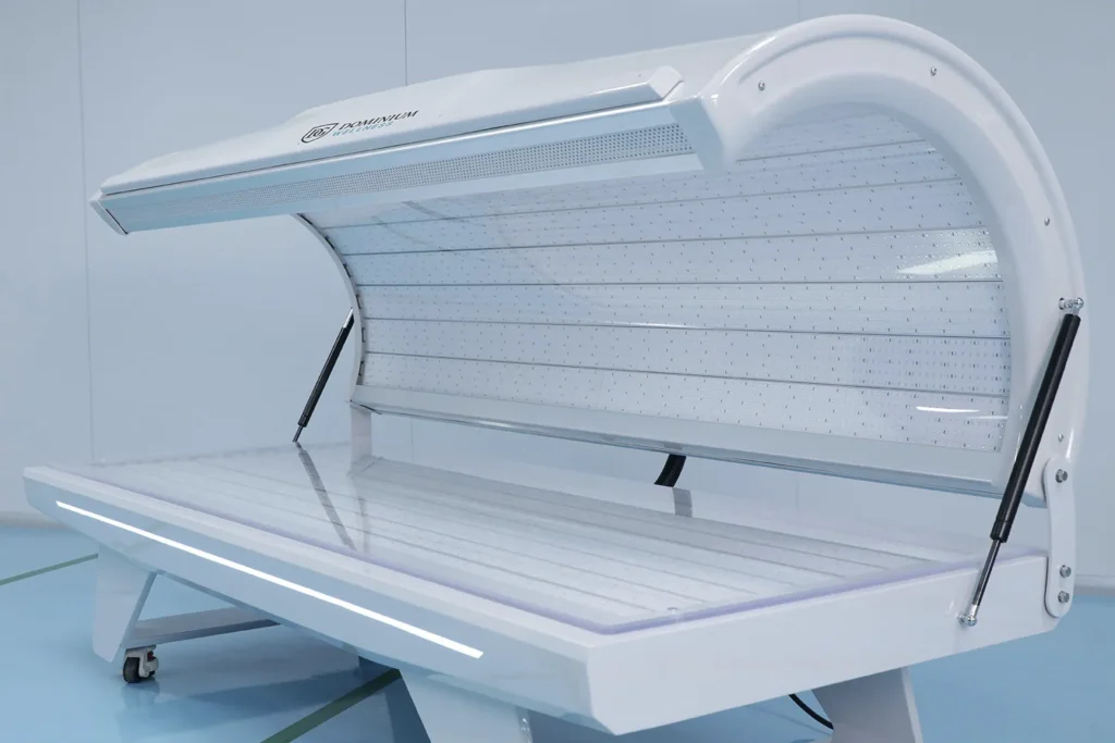 Bočni pogled na otvorenu belu elegantnu visokotehnološku hiperbaričnu kiseoničku komoru Dominium Wellness, model DWRB Comfort, sa naglaskom na moderan spoljašnji dizajn.